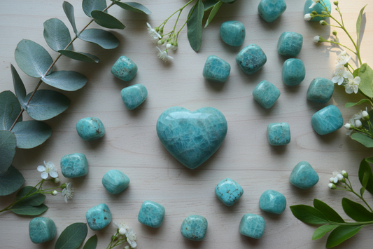 Turquoise amazoniet stenen en hart op houten ondergrond met eucalyptustakjes, witte bloemen en groene bladeren in zacht koel licht