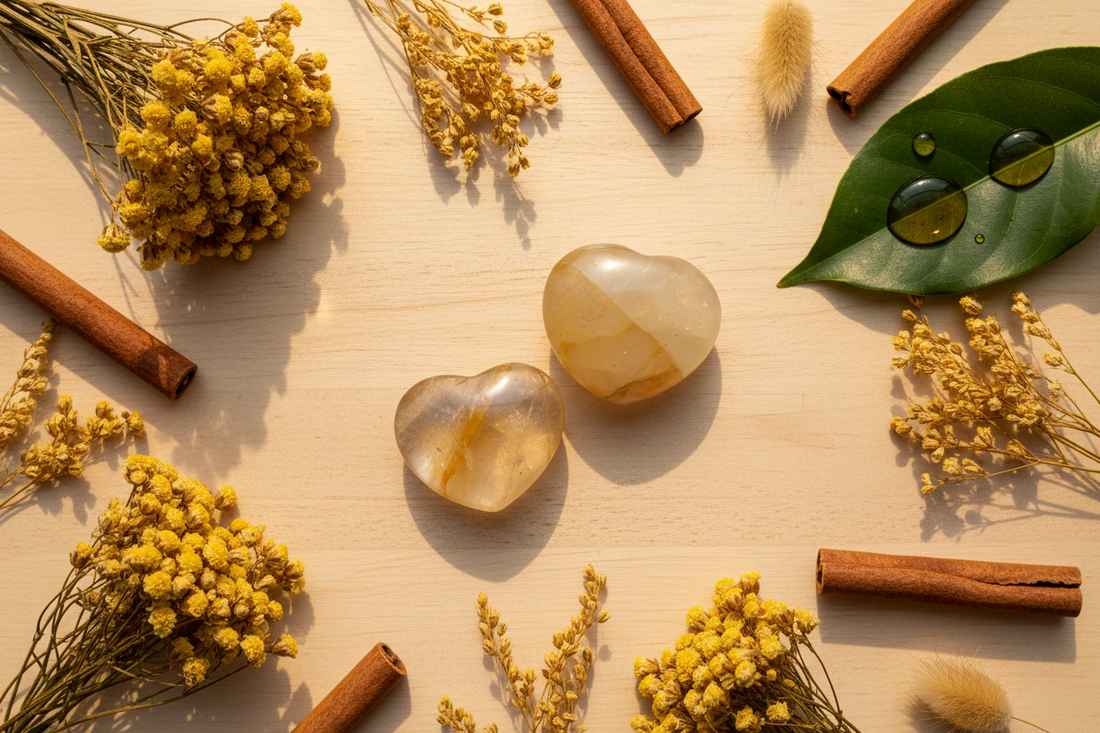 Twee warme honinggouden Golden Healer kwarts hartjes op houten ondergrond met droge gele bloemen, gouden grassen en kaneelstokjes in zacht warm gouden licht