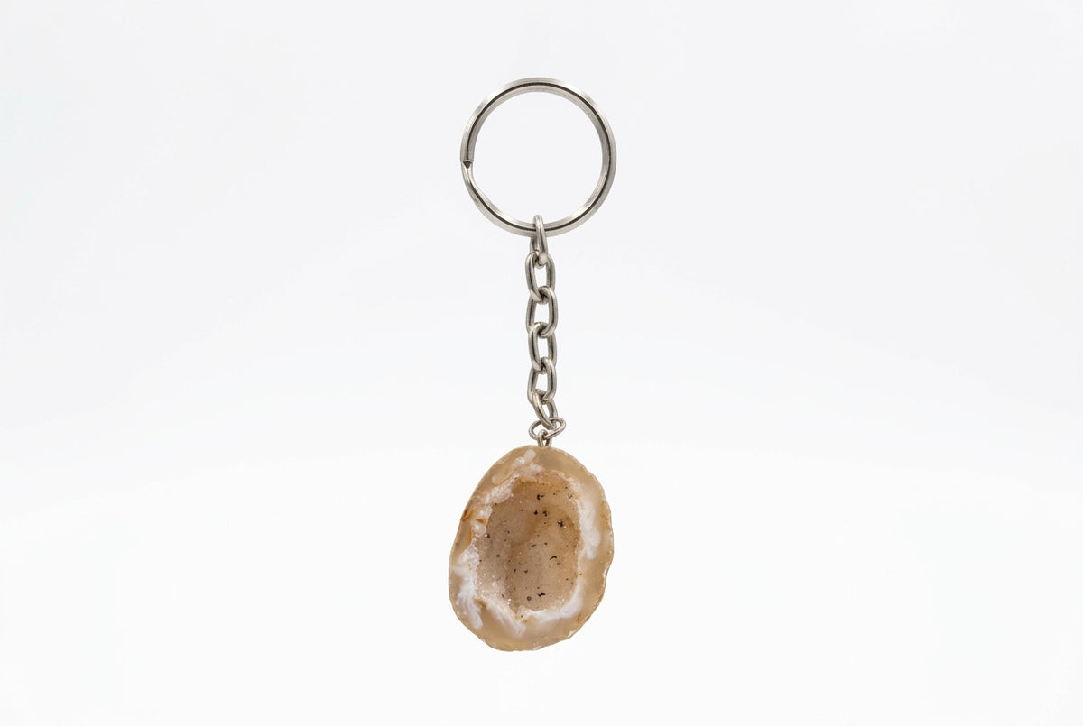 Beige agaat sleutelhanger met een lichte rand en donkere spikkeltjes, met zilverkleurige ketting en sleutelring