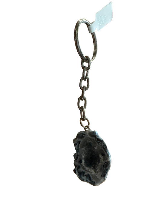 Donkergrijze agaat sleutelhanger met golvende lichte banden rond een donker midden, met zilverkleurige ketting en sleutelring