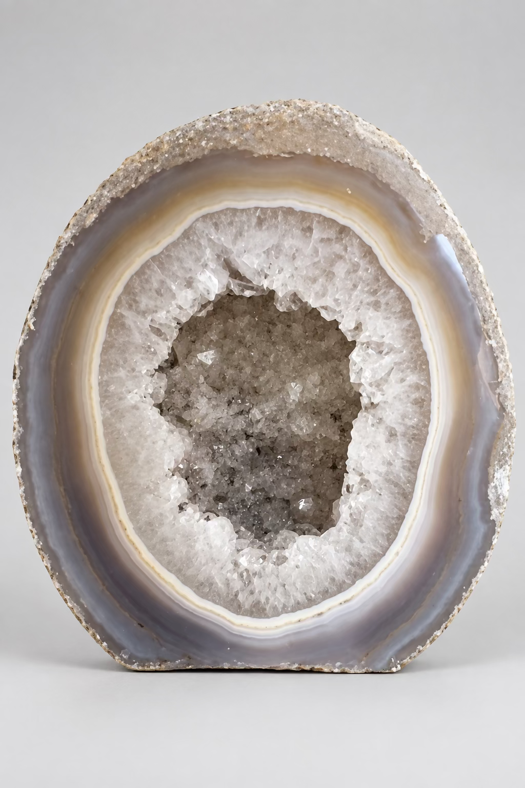 Agaat mini geode met grijze, beige en crèmekleurige banden rondom een open holte met glinsterende druzy