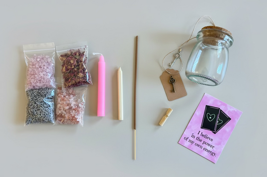 Glazen potje met rozenkwarts, lavendel, rozenblaadjes en roze kaarsvet erbovenop